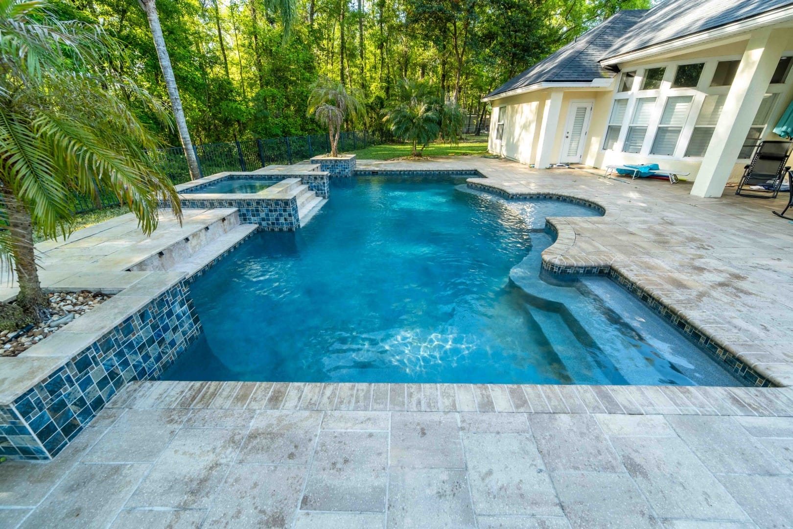 Big irregular pool next to a house and a forest